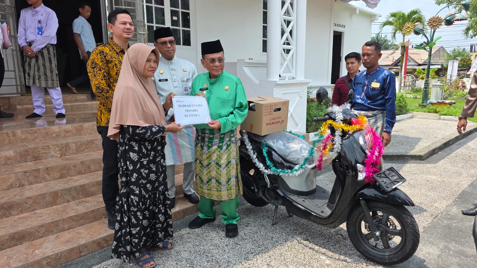 Foto : Foto : Bupati Rokan Hilir Haji Bistamam, didampingi Sekretaris Daerah (Sekda) Rokan Hilir Fauzi Efrizal dan Direktur Utama BPR Rokan Hilir Wan Muhamad Kudri saat menyerahkan hadiah utama program Simaris kepada nasabah Warsini, Jum'at (21/08/2026).
